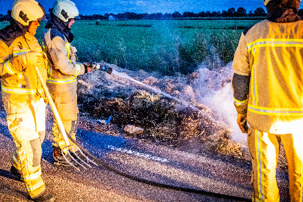 Brandweer blust broei in stro langs weg in Nijeveen — Nijeveen
